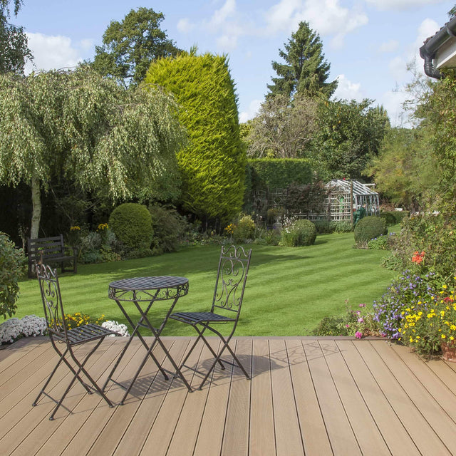 Backyard with brown composite deck and bistro furniture set overlooking a well-maintained garden.