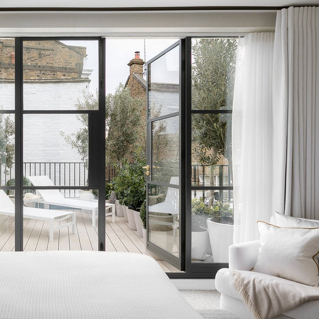 Modern living room with large glass doors leading to a patio area with sun loungers on a light grey composite deck.